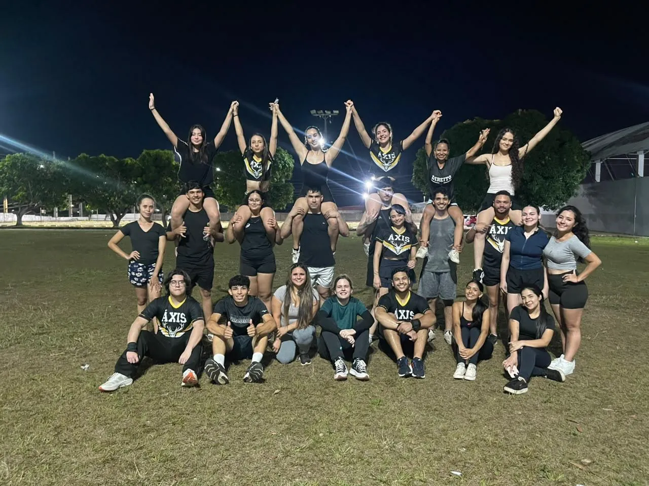 A equipe inteira num gramado à noite, com atletas erguidas pelos colegas